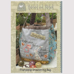 May include: A fabric drawstring bag featuring a gray front panel with embroidered text that reads Forever Friends and No matter where they are... friends are never far. The bag has light blue floral side panels, brown handles, and a yellow base.