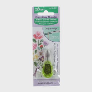 May include: A Clover brand embroidery threader, Art No. 8611, in a package with text in multiple languages. The threader is green and clear, designed for smooth threading even with thick threads. The package features floral embroidery art.