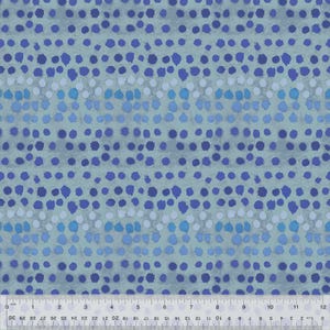 May include: A fabric with a repeating pattern of blue dots on a light blue background. The dots vary in size and shade, creating a textured appearance. A ruler is at the bottom, showing inches.