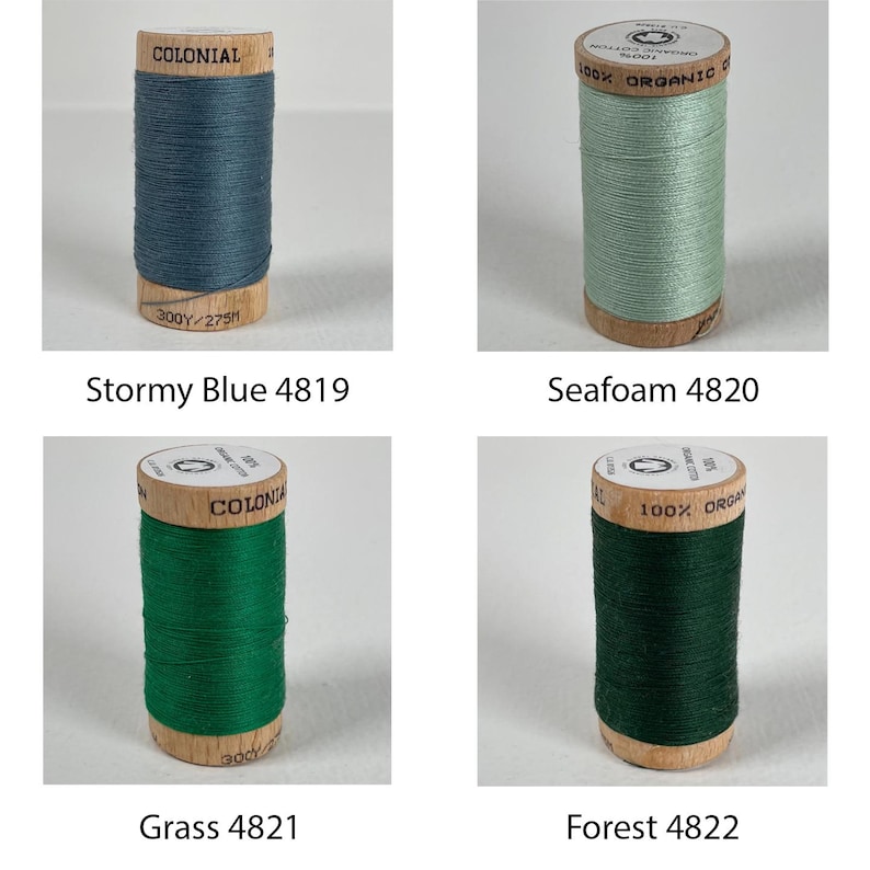 K&ouml;nnte beinhalten: Vier Spulen mit 100% Bio-Baumwollgarn in verschiedenen Blaut&ouml;nen und Gr&uuml;nt&ouml;nen. Die Spulen sind mit "Colonial" und "100% Bio-Baumwolle" beschriftet. Die Farben sind Stormy Blue 4819, Seafoam 4820, Grass 4821 und Forest 4822.