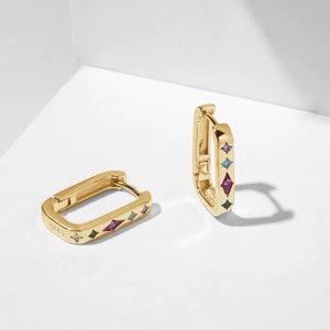 May include: Gold hoop earrings with a rectangular shape and colourful gemstones set in the metal. The gemstones are in a variety of colours, including blue, green, pink, and purple.