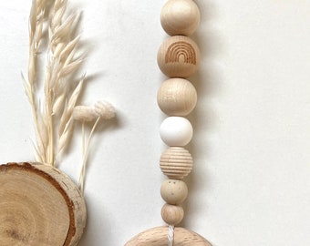 May include: A wooden baby teether with a rainbow design and a white bell. The teether is made of natural wood and has a ring for easy gripping.