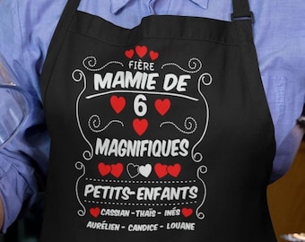 May include: Black apron with white text that reads "Fière Mamie de 6 Magnifiques Petits-Enfants Cassian - Thaïs - Inés Aurélien - Candice - Louane".