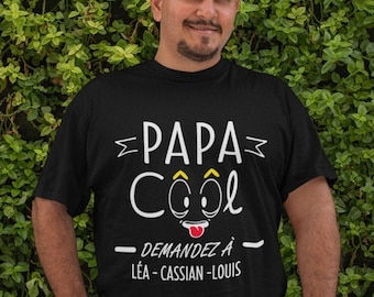 May include: Black t-shirt with white text that reads "Papa Cool - Demandez à Léa - Cassian - Louis". The text is surrounded by a white border and includes a cartoon face with a tongue sticking out.