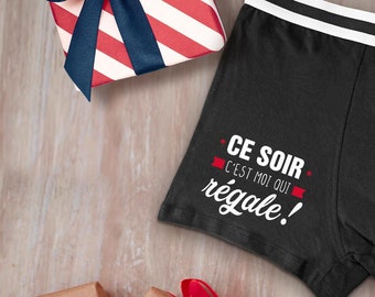 May include: Black boxer shorts with a white waistband and the text "CE SOIR C'EST MOI QUI REGALE!" printed in white.