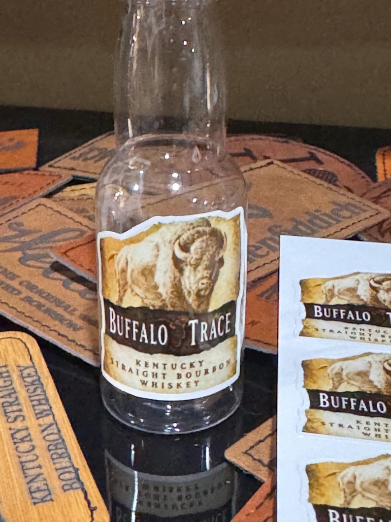 May include: A small glass bottle of Buffalo Trace Kentucky Straight Bourbon Whiskey. The bottle has a brown label with a white buffalo silhouette and the text "Buffalo Trace Kentucky Straight Bourbon Whiskey".