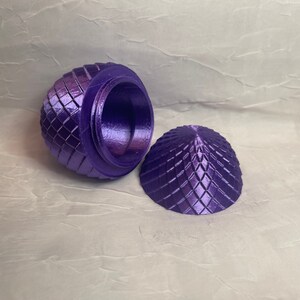 May include: A purple, 3D printed egg-shaped trinket box with a geometric pattern. The lid is open, revealing the empty interior.