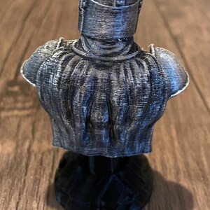 May include: A 3D printed bust of a character wearing a silver helmet and armor. The bust is on a black base.