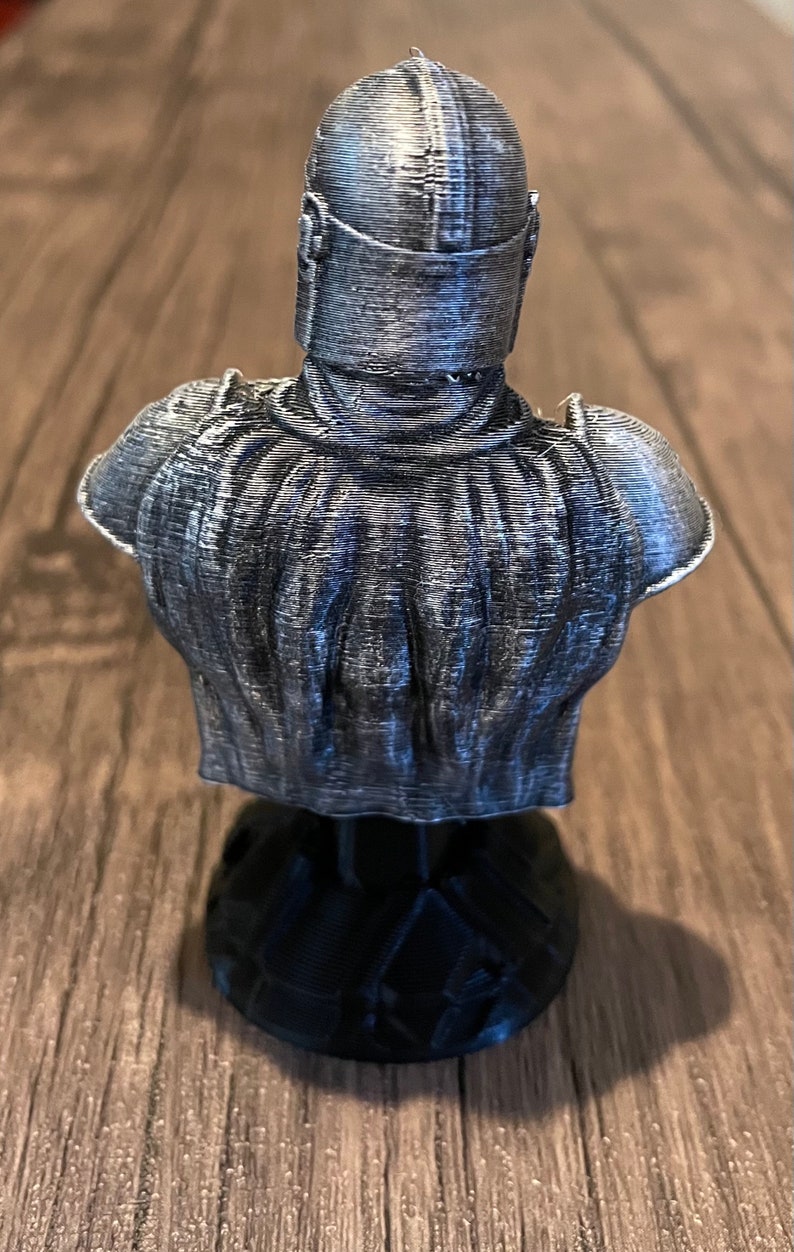 May include: A 3D printed bust of a character wearing a silver helmet and armor. The bust is on a black base.