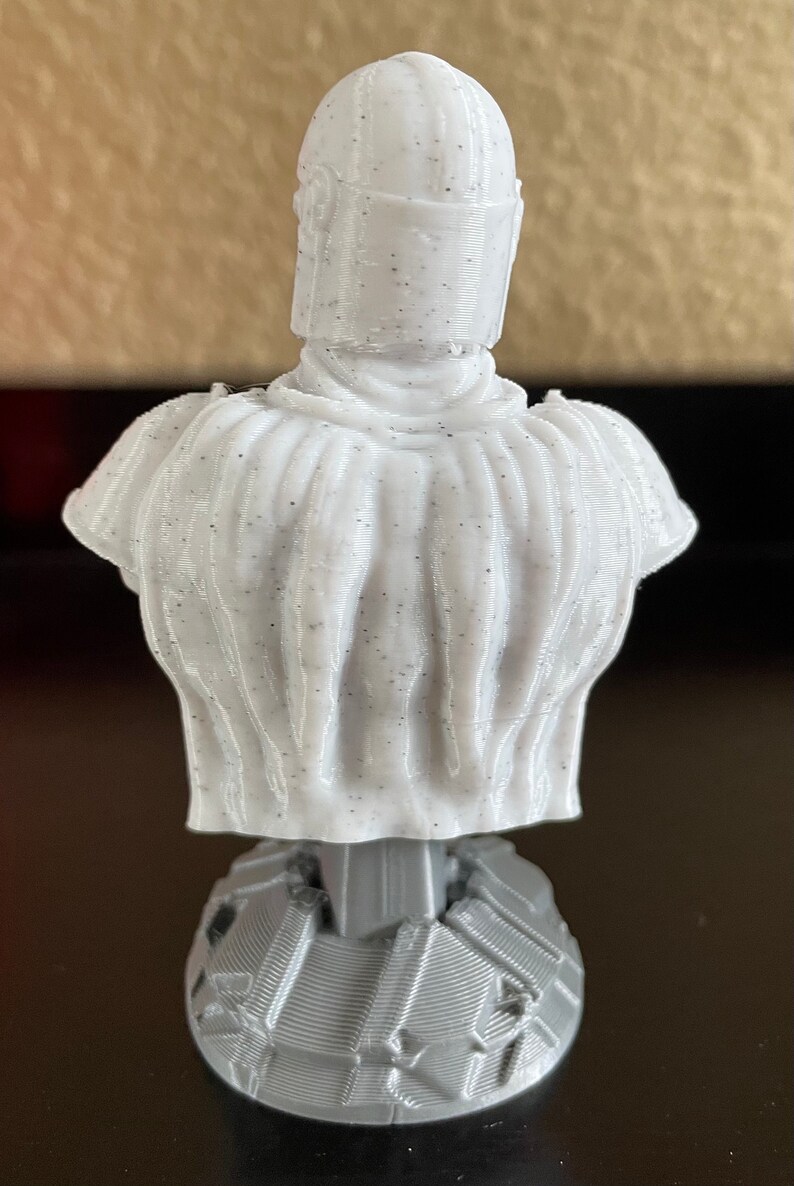May include: A white 3D printed bust of a character wearing a helmet. The bust is on a gray base.