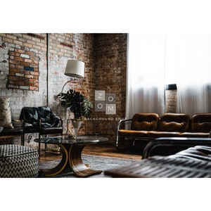 May include: An interior shot of a room with exposed brick walls, featuring a brown leather sofa, chairs, and a round wooden coffee table. A floor lamp with a white shade and a large plant are also visible. The room has a vintage, industrial aesthetic.