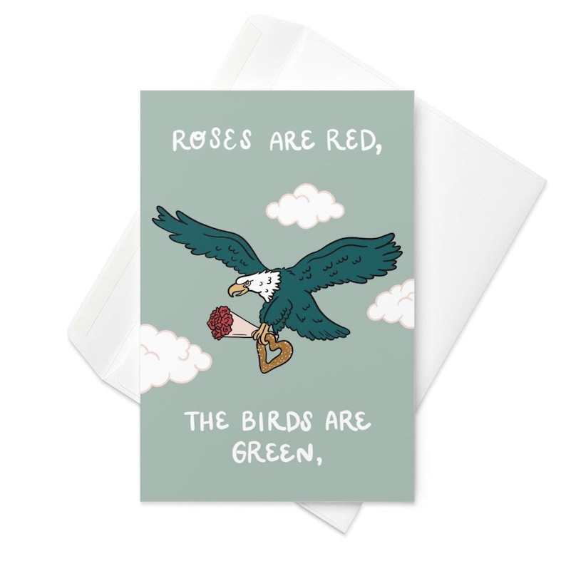 May include: Greeting card with a cartoon eagle carrying a bouquet of red roses and a heart-shaped key. The card has the text "Roses are red, the birds are green," on a light green background, with white clouds.