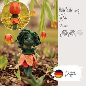 Könnte beinhalten: Häkel-Amigurumi-Puppe einer grünen Fee mit orangenen Blütenblättern für einen Rock. Die Puppe steht in einem Bett aus grünem Moos und orangenen Blumen. Das Bild enthält den Text "Häkelanleitung Jafa Tulppani Deutsch".