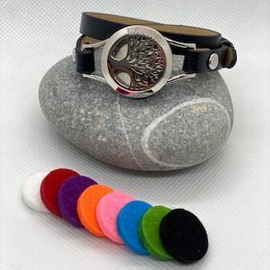 May include: A black leather diffuser bracelet with a silver tree of life charm. The bracelet comes with a set of colourful felt pads for adding essential oils.