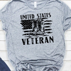 May include: Gray t-shirt with a distressed American flag design and a pair of black boots. The text "United States Veteran" is printed below the flag.