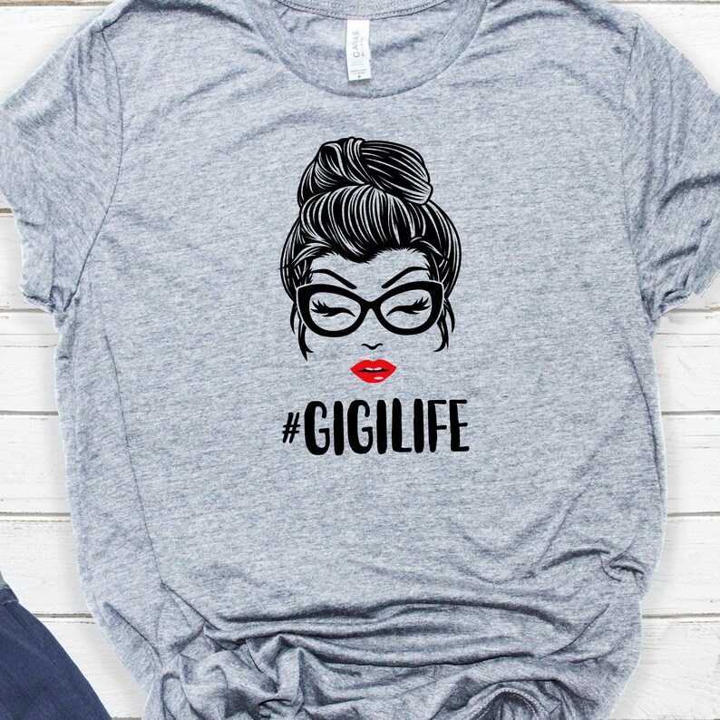 May include: Gray t-shirt with a black and white illustration of a woman with a bun, glasses, and red lips. The text "#GIGILIFE" is printed below the illustration.