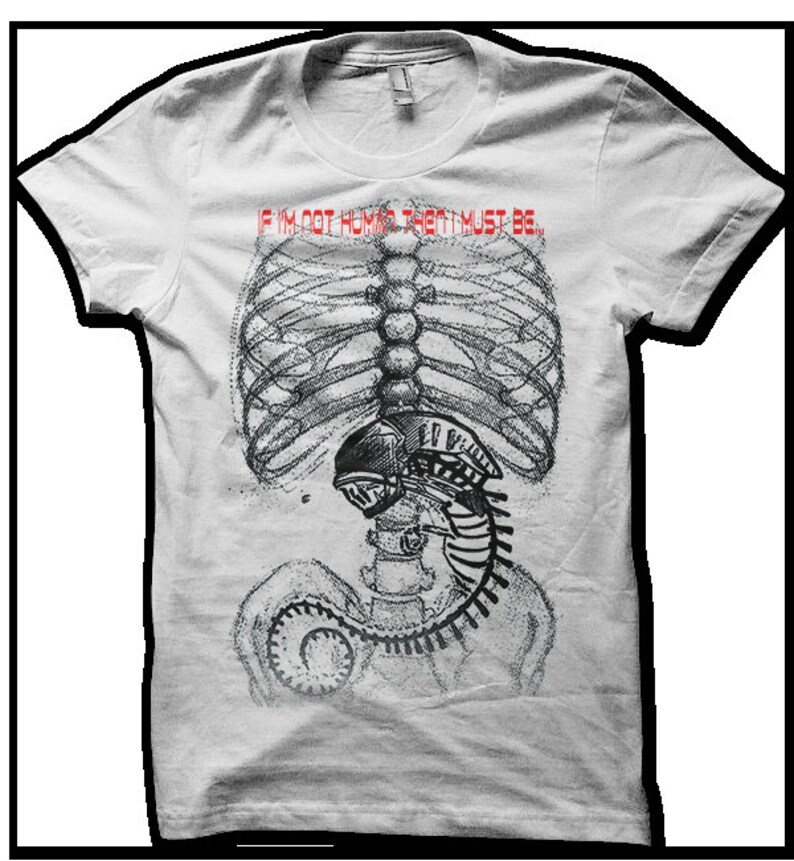 Puede incluir: Camiseta blanca con un estampado gr&aacute;fico de un esqueleto con una criatura alien&iacute;gena dentro de su caja tor&aacute;cica. El texto "If I'm not human then I must be..." est&aacute; impreso en rojo sobre el gr&aacute;fico.