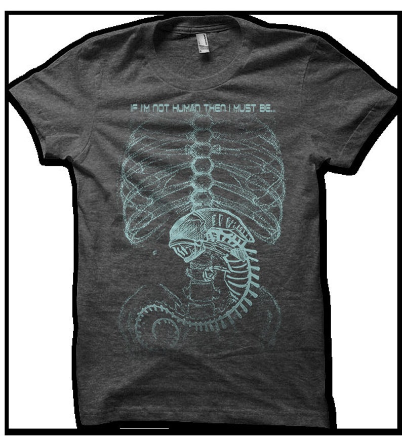 Puede incluir: Una camiseta gris jaspeada con un estampado gr&aacute;fico de una caja tor&aacute;cica esquel&eacute;tica y una criatura extraterrestre en su interior. El texto "IF I'M NOT HUMAN THEN I MUST BE..." est&aacute; impreso sobre el gr&aacute;fico.
