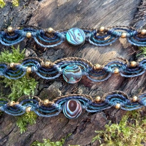 Può includere: Tre braccialetti in macramè fatti a mano con cordoncini blu e marroni e perline di abalone iridescenti.