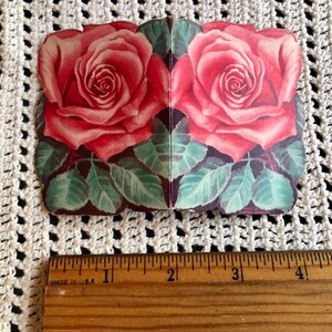 May include: A vintage Valentine's Day card featuring two pink roses with green leaves. The card is folded in half and has a white background.