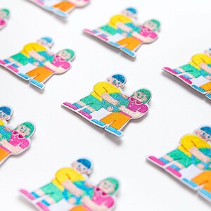 May include: Set of embroidered iron-on patches featuring three figures holding each other. The figures are in various colors, including yellow, green, pink, and blue. The patches are perfect for adding a touch of personality to clothing, bags, or other accessories.