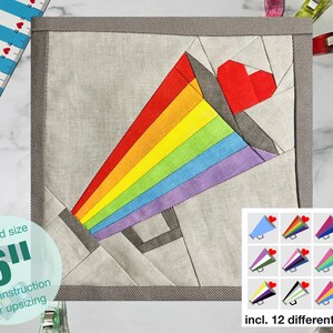 May include: A 6-inch square fabric quilt block featuring a rainbow megaphone with a red heart. The block is made of various fabrics, including gray, white, and rainbow colors. The image also includes a smaller image of 12 different megaphone designs with various colors and hearts.