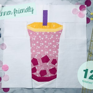 Puede incluir: Un patrón de bloque de colcha de 30,5 cm fácil para principiantes, que presenta una taza de té de burbujas rosa y amarilla con una pajita morada. El patrón está formado por piezas de tela de diferentes formas y tamaños.