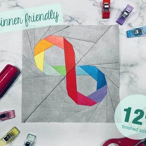 May include: Beginner friendly 12 inch quilt block pattern featuring a colorful infinity symbol design. The pattern is drawn on a gray fabric background.