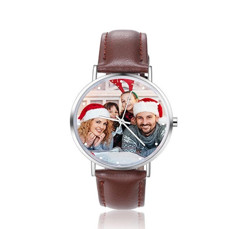 May include: A brown leather wristwatch with a silver face. The face of the watch has a photo of a family wearing Santa hats.
