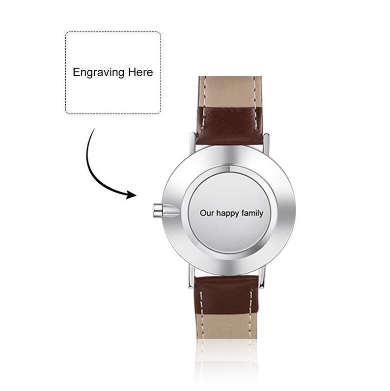 May include: A silver wristwatch with a brown leather band. The watch face is blank and has a space for engraving. The text "Our happy family" is engraved on the back of the watch.