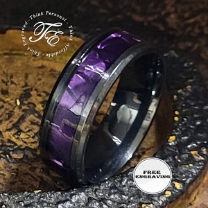 May include: Black tungsten carbide ring with a purple and white camouflage inlay. The ring is polished and has a beveled edge. Free engraving is offered.