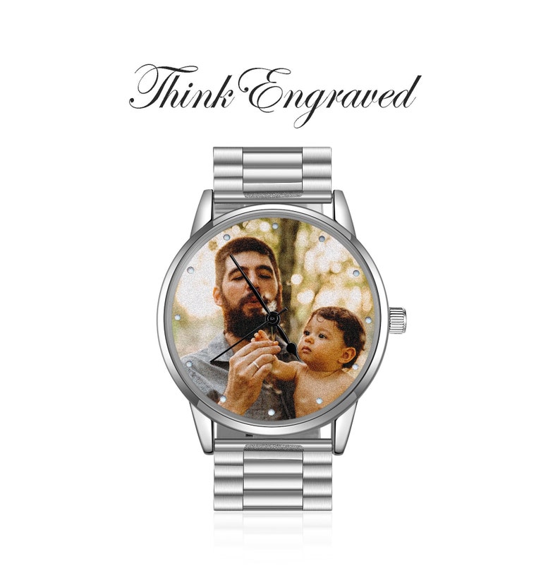 May include: A silver wristwatch with a round face featuring a photo of a man and a child. The watch has a silver metal band.