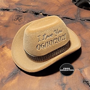 May include: A brown felt cowboy hat with a black band and the words "I Love You 06/10/2021" engraved on the crown.