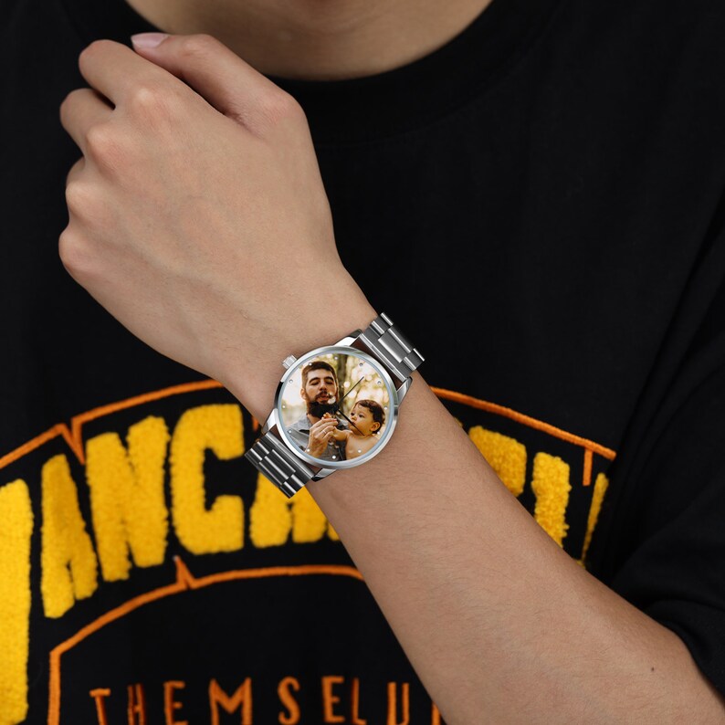 May include: A silver wristwatch with a round face featuring a photo of a man and a child. The watch has a metal band.