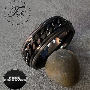 May include: Black spinning ring with a chain design. The ring is made of stainless steel and has a brushed finish. Free engraving is offered.