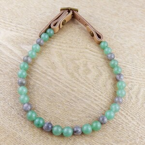 May include: A green and grey beaded necklace with a leather strap closure.