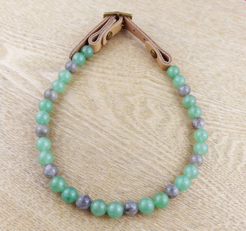 May include: A green and grey beaded necklace with a leather strap closure.