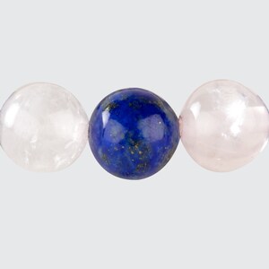 May include: Three round gemstone beads, one blue, two pink. The blue bead is in the center, and the pink beads are on either side.