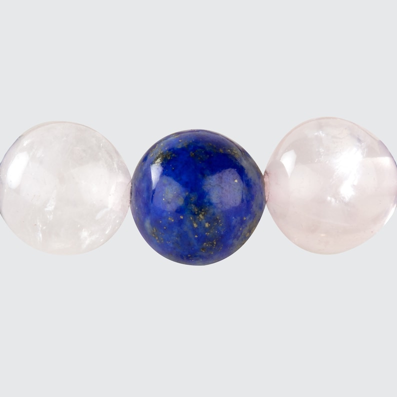 May include: Three round gemstone beads, one blue, two pink. The blue bead is in the center, and the pink beads are on either side.