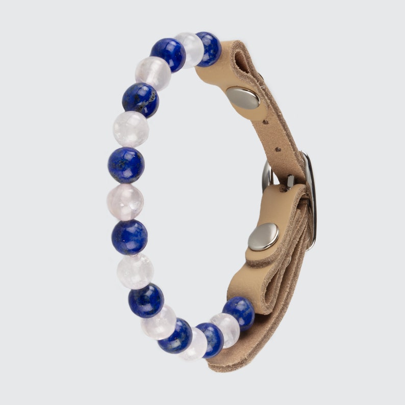 May include: A tan leather bracelet with a silver buckle and a row of blue and white beads.