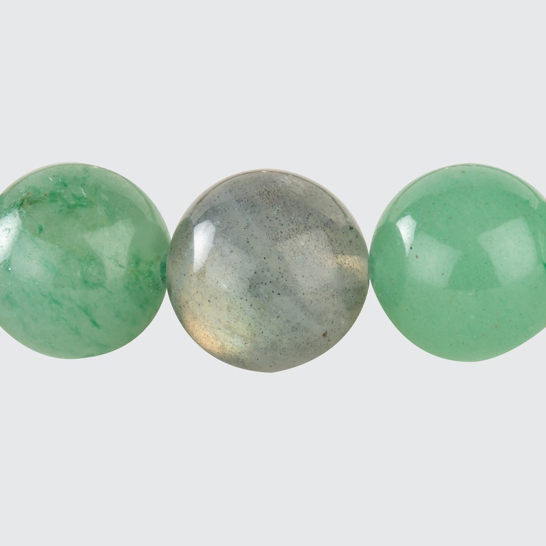 May include: Three round beads, one green, one grey, and one green. The beads are smooth and polished.