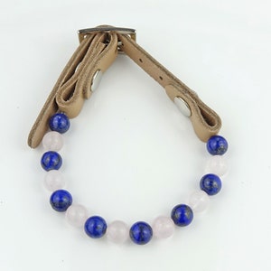 May include: A brown leather bracelet with a silver buckle and a string of blue and pink beads.