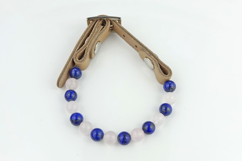 May include: A brown leather bracelet with a silver buckle and a string of blue and pink beads.