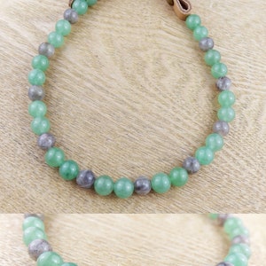 May include: A green and grey beaded necklace with a leather strap closure. The necklace is made of round beads and is approximately 18 inches long.