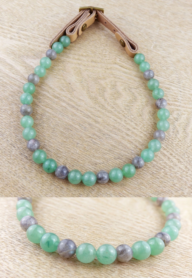 May include: A green and grey beaded necklace with a leather strap closure. The necklace is made of round beads and is approximately 18 inches long.