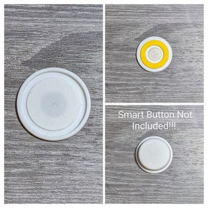 Puede incluir: Una base de plástico blanca para un botón inteligente, un botón inteligente amarillo y blanco, y un botón inteligente blanco con la palabra "hue" impresa en él. El texto "Smart Button Not Included!!!" está impreso en la imagen.