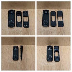 Op de afbeelding: Een gedemonteerde zwarte deurbelcamera met een lens, een voorplaat en een achterplaat.