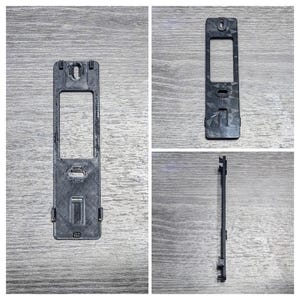 May include: Three black plastic wall plates with a rectangular opening in the center. The plates have a textured surface and are designed for mounting.