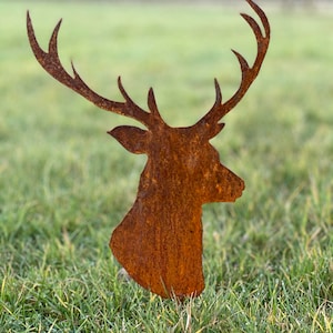 May include: A rusty metal deer head silhouette, standing in a grassy field. The deer's antlers are large and spread out.