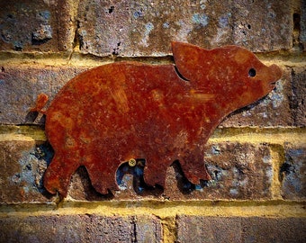 May include: A rusty metal pig silhouette mounted on a brick wall. The pig is facing right and has a slightly curved snout.